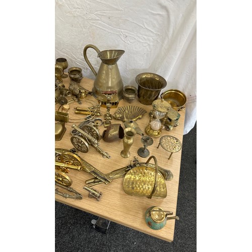 102 - Large selection of brass ware items to include jugs, ornaments, oil lamps, canons, egg timer etc