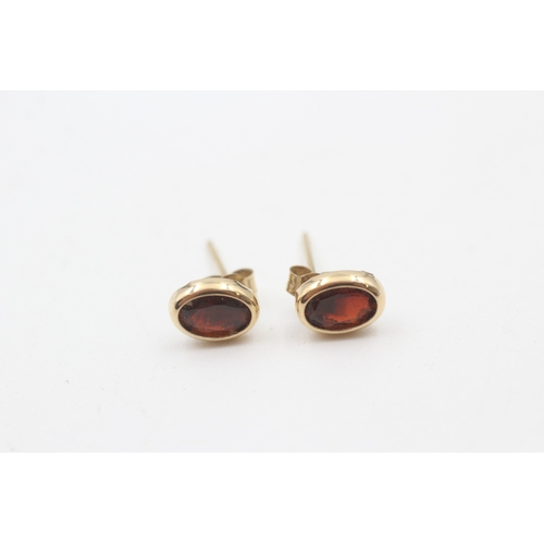 201 - 9ct gold oval cut garnet stud earrings (0.7g)