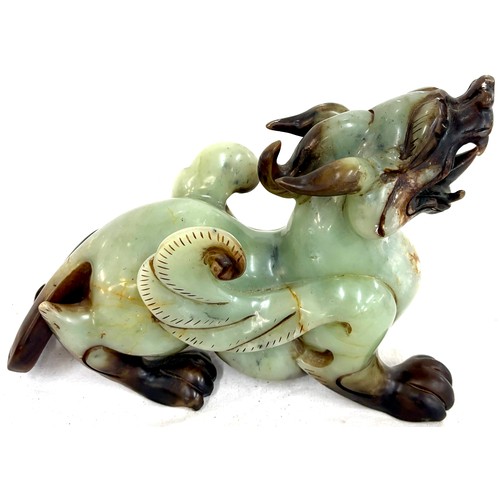 A large Chinese possibly jade dragon, in green & brown colours, in recoiled stance with snarling mouth, approximate measurements: Height 8 inches, Length 11 inches, Depth 4 inches