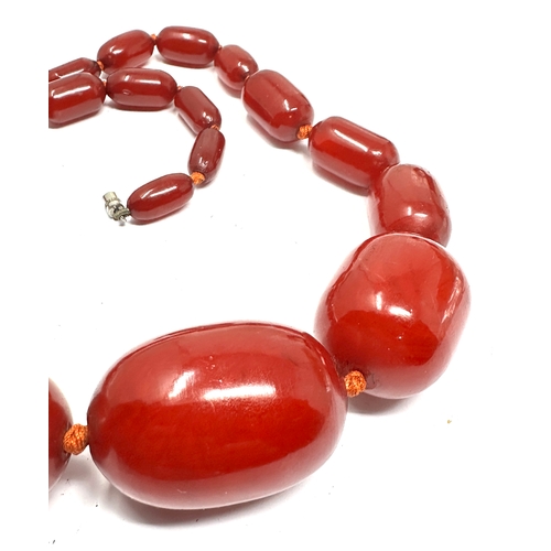 205 - Very large cherry amber / bakelite bead necklace largest central bead measures approx 43mm by 24mm t... 