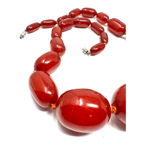 205 - Very large cherry amber / bakelite bead necklace largest central bead measures approx 43mm by 24mm t... 