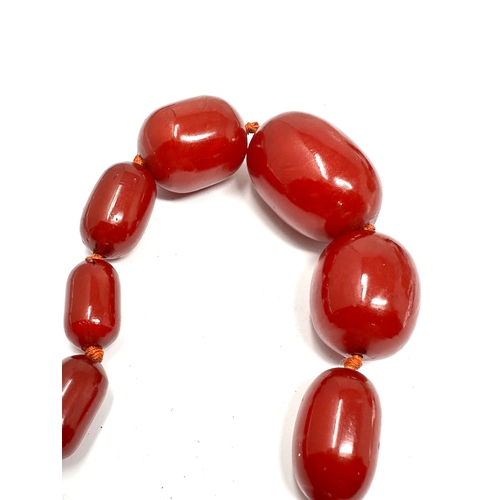 205 - Very large cherry amber / bakelite bead necklace largest central bead measures approx 43mm by 24mm t... 