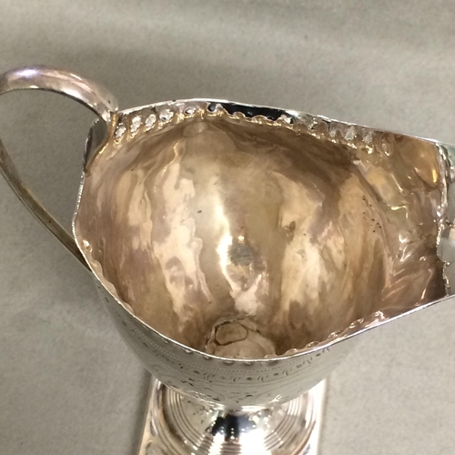 110 - A Georgian sterling silver cream jug with punched decoration raised on a square foot, London 1834 , ... 