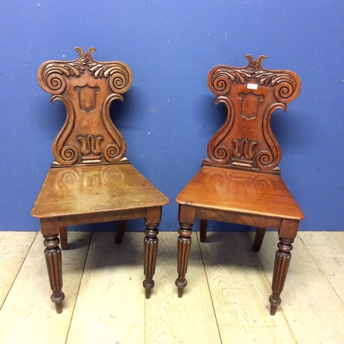 540 - Pair of mahogany shield shaped back hall chairs, with some wear and fading