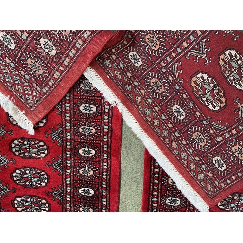 587 - Two Pakistan Bokhara handknotted wool red ground rugs, with central panel of lozenge patterns, and s... 