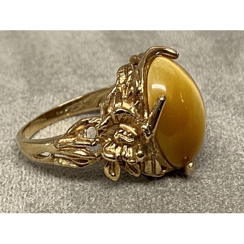 73 - Yellow metal and Tigers eye ring marked 10k, central oval Tigers eye with cast and pierced shoulders... 