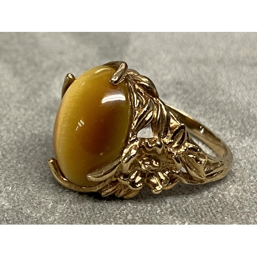 73 - Yellow metal and Tigers eye ring marked 10k, central oval Tigers eye with cast and pierced shoulders... 