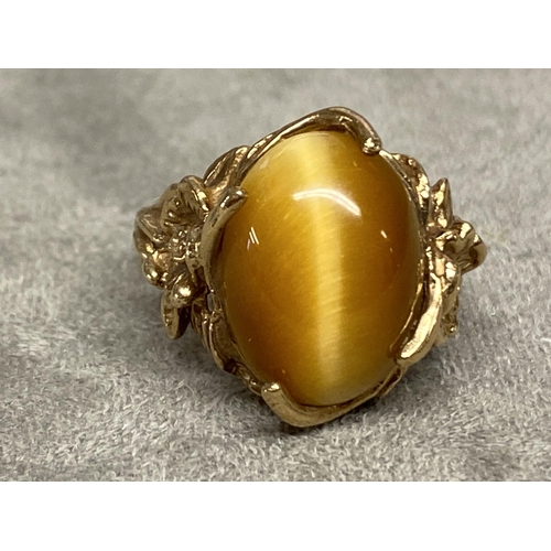 73 - Yellow metal and Tigers eye ring marked 10k, central oval Tigers eye with cast and pierced shoulders... 