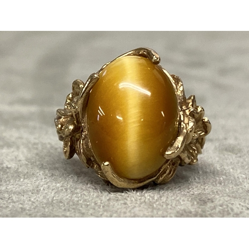 73 - Yellow metal and Tigers eye ring marked 10k, central oval Tigers eye with cast and pierced shoulders... 