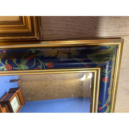 438 - A decorative mirror with hand painted floral and gold coloured border and a framed and glazed moorla... 