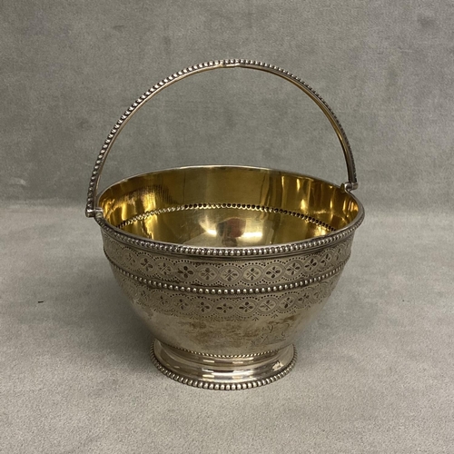 11 - A Victorian sterling silver bowl, swing handle with chased decoration, beaded rim and gilt interior ... 