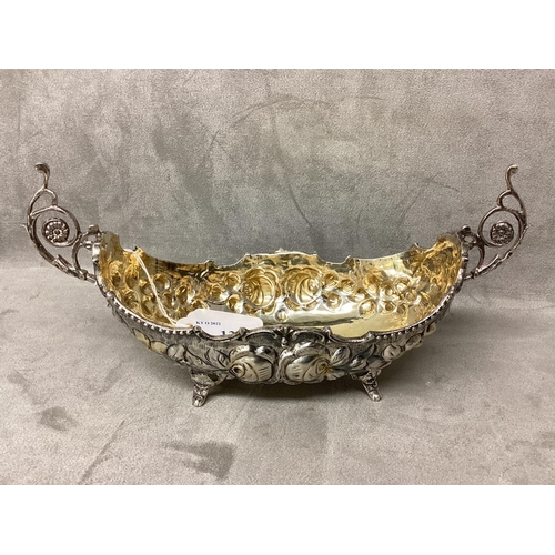 13 - Silver boat shaped dish with scrolling handles chased decoration on 4 feet, marked to base, first cl... 