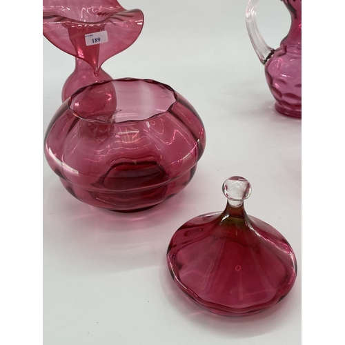 189 - A collection of cranberry glass items to include Jack in a Pulpit vase, lidded bowl, a pair of vases... 