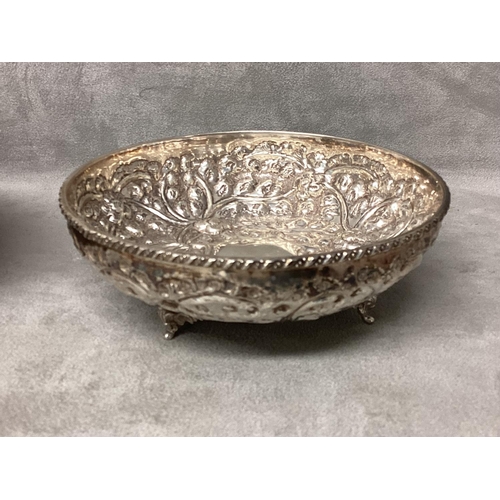 23 - Pair of Middle Eastern white metal bowls with raised floral decoration raised on three feet, 14 x 5c... 