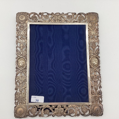 30 - A solid silver pierced easel backed picture frame with cast classical busts and roundels, 30 x 25cm