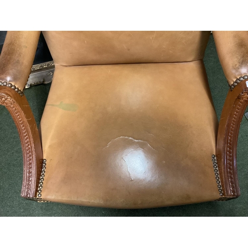 496 - Large winged back light tan and studded brass leather arm chair, on 4 legs to castors