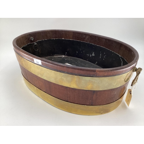 136 - A wooden and brass bound planter with tin interior. Size: oval 60cm x 38 cm x 20 cm height with hand... 