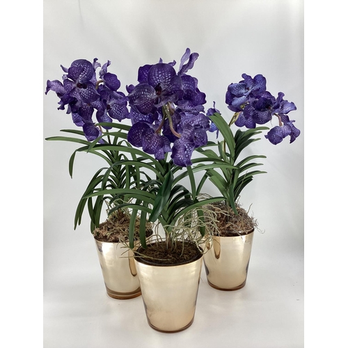 217 - Three  impressive faux flowers, of purple orchid arrangements in glass containers, and mirrored plan... 