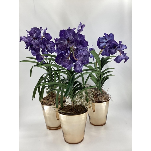 217 - Three  impressive faux flowers, of purple orchid arrangements in glass containers, and mirrored plan... 