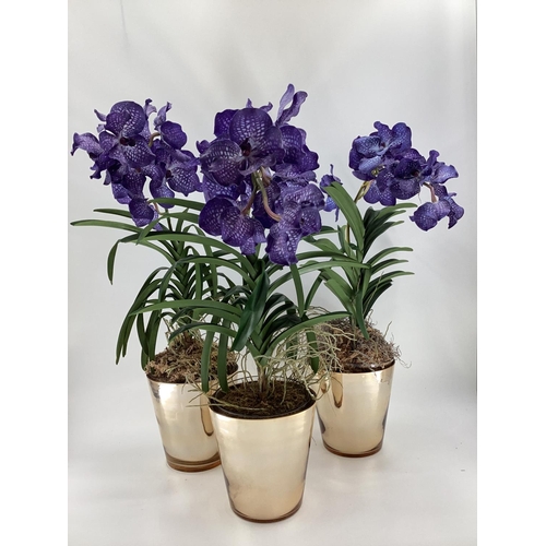 217 - Three  impressive faux flowers, of purple orchid arrangements in glass containers, and mirrored plan... 