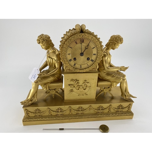 234 - Gilded French mantle clock, flanked by figures of Grecian women sat on Regency style cross stretcher... 