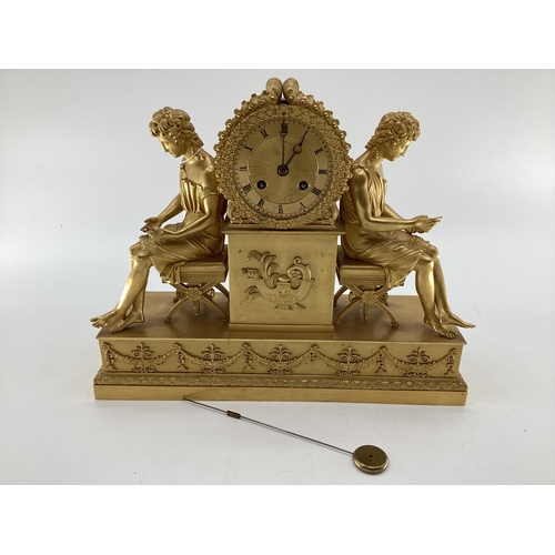 234 - Gilded French mantle clock, flanked by figures of Grecian women sat on Regency style cross stretcher... 