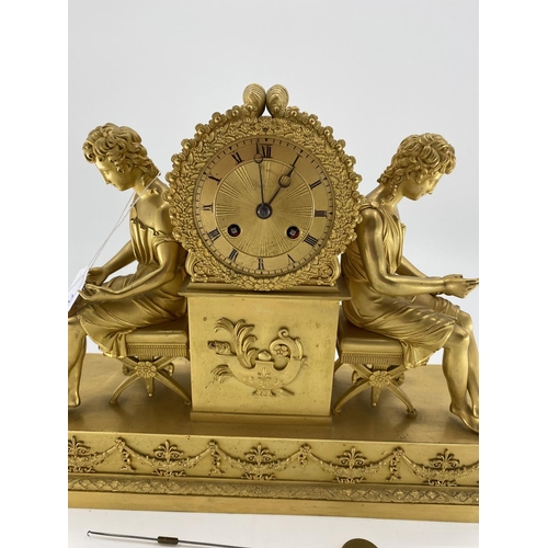 234 - Gilded French mantle clock, flanked by figures of Grecian women sat on Regency style cross stretcher... 