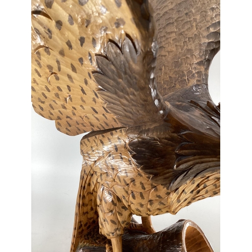 310 - A wooden and resin model of a swooping Eagle on a tree stump (wing detachable) 74 cm x 75 cm x 32 cm