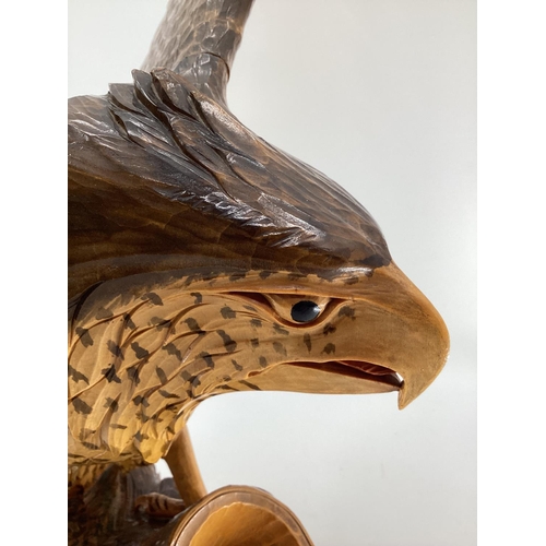 310 - A wooden and resin model of a swooping Eagle on a tree stump (wing detachable) 74 cm x 75 cm x 32 cm