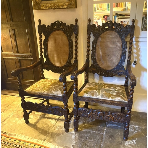 574 - Pair of good Jacobean style heavily carved mahogany arm chairs, with bergere cane backs and upholste... 