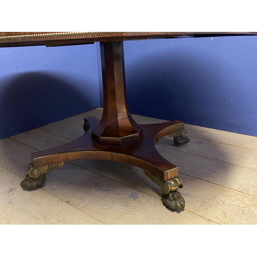 614 - A good Regency mahogany and rosewood circular snap top dining table, with brass edgings, on an octag... 