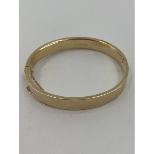 93 - A 9ct gold bangle bracelet with chased decoration, 12.4g