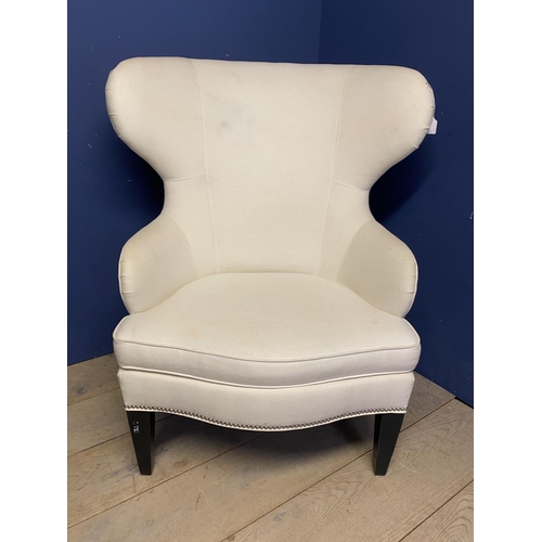 576 - An oversized modern wing backed arm chair, upholstered in cream fabric and brass studded , 120cm H o... 