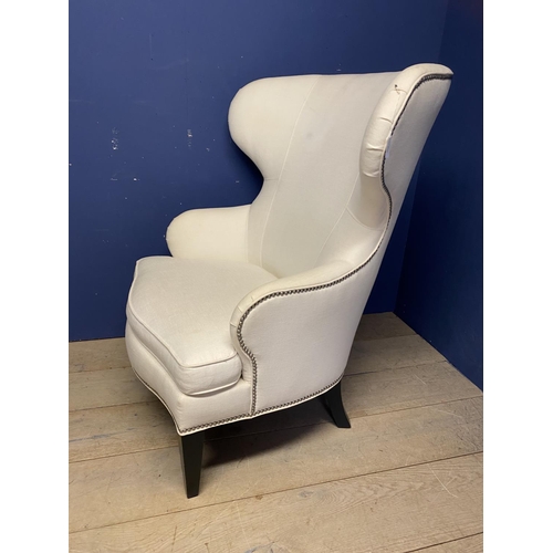 576 - An oversized modern wing backed arm chair, upholstered in cream fabric and brass studded , 120cm H o... 