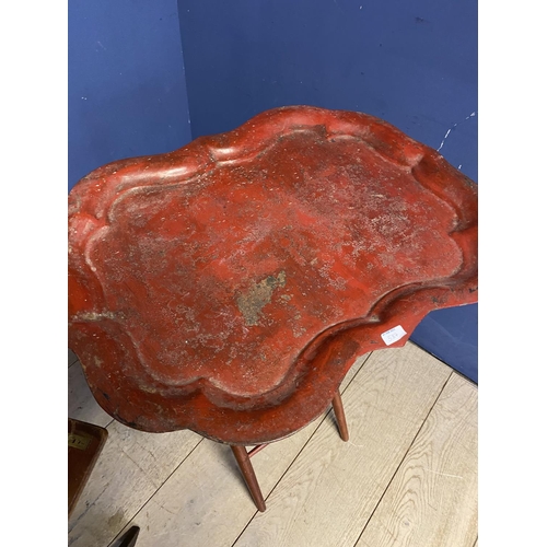 587 - A mahogany and brass hinged folding  butlers tray on a folding stand; and a worn red lacquered shape... 