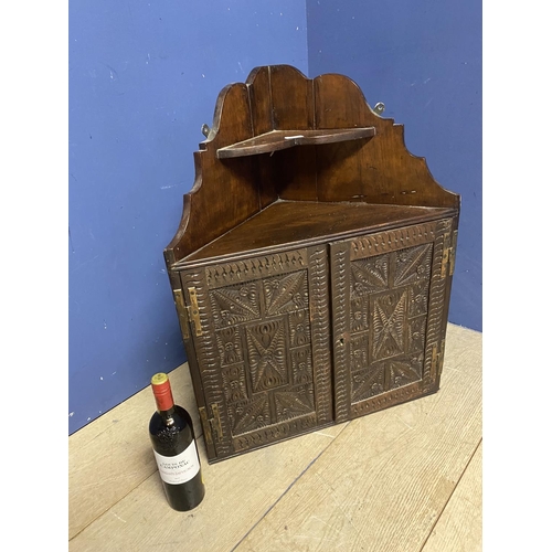 588 - AN oak hanging wall cabinet, with carved wooden doors below a corner shelf, some minor wear, 30cm H ... 