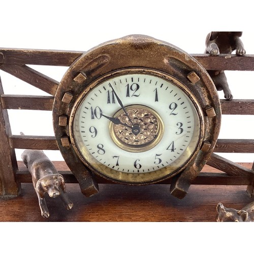 307 - A desk clock, depicting model of Fox and Hounds at a farm gate, 28cm Wide, on a wooden plynth