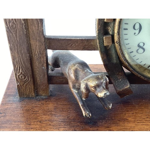 307 - A desk clock, depicting model of Fox and Hounds at a farm gate, 28cm Wide, on a wooden plynth