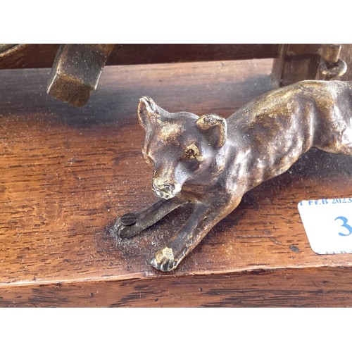 307 - A desk clock, depicting model of Fox and Hounds at a farm gate, 28cm Wide, on a wooden plynth