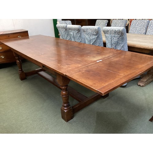 560 - A large heavy oak extending dining table, with solid stretcher to base, 307cm with both ends extende... 