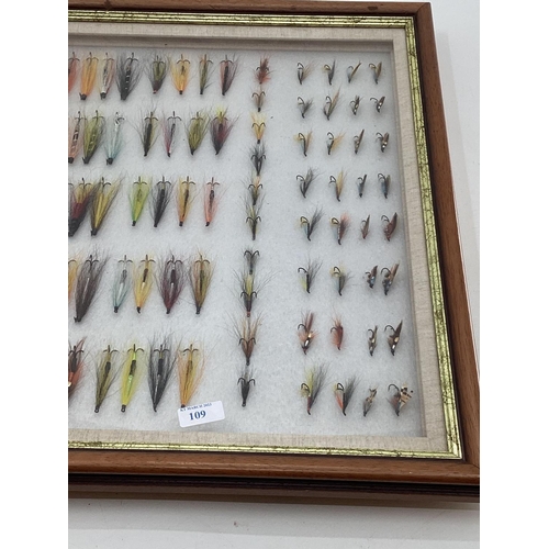 109 - A collection of fishing flies in a boxed glass display frame 58 x 67cm