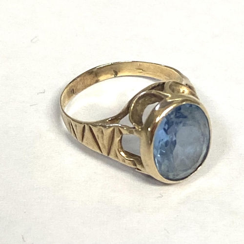 56 - An unmarked yellow metal and aquamarine ring, central oval free cut aquamarine in a bezel setting, s... 