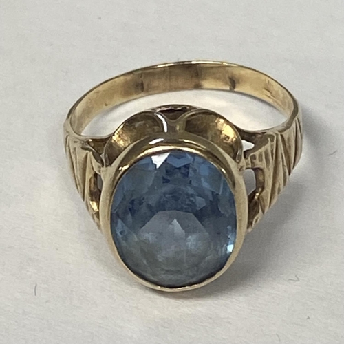 56 - An unmarked yellow metal and aquamarine ring, central oval free cut aquamarine in a bezel setting, s... 