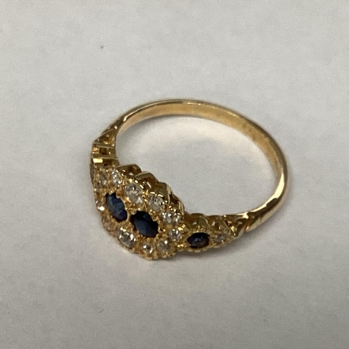 40 - An unmarked yellow metal diamond and sapphire ring two central round cut sapphires with a surround o... 