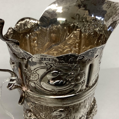 6 - A Sterling silver cream jug, decorated with repousse farmyard scenes on 3 paw feet by John Millward ... 