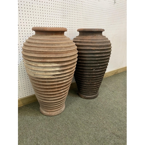 73 - Two similar terracotta tall ribbed hoop pattern urns/pots, 65cm H