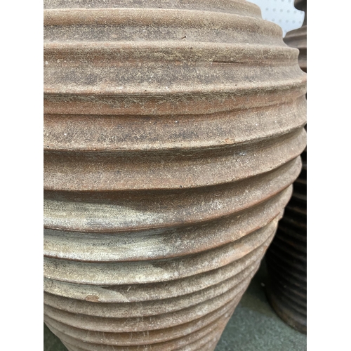 73 - Two similar terracotta tall ribbed hoop pattern urns/pots, 65cm H