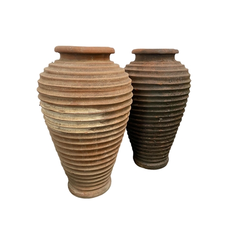 73 - Two similar terracotta tall ribbed hoop pattern urns/pots, 65cm H