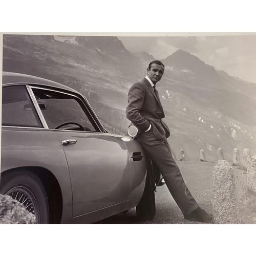 369 - A large photographic print of Sean Connery, leaning against his Aston Martin DB5, screen shot from t... 