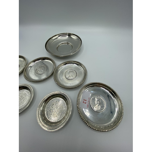 12 - A set of 4 silver coin set pin dishes and a sterling silver example and 2 unmarked white metal Middl... 